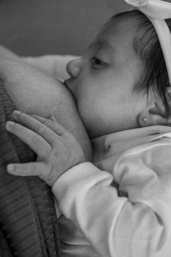 Black and white portrait of a mother breastfeeding her newborn child, showcasing love and tenderness.